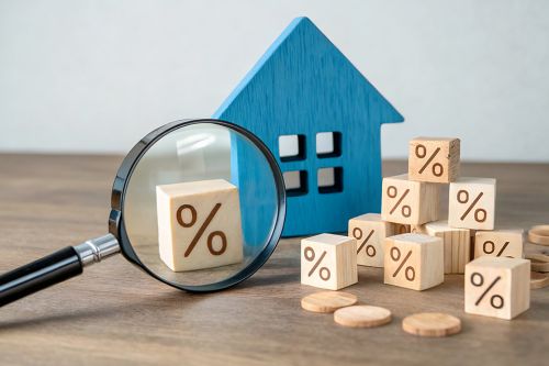 Lupe, Holzhaus und Würfel mit Prozentzeichen